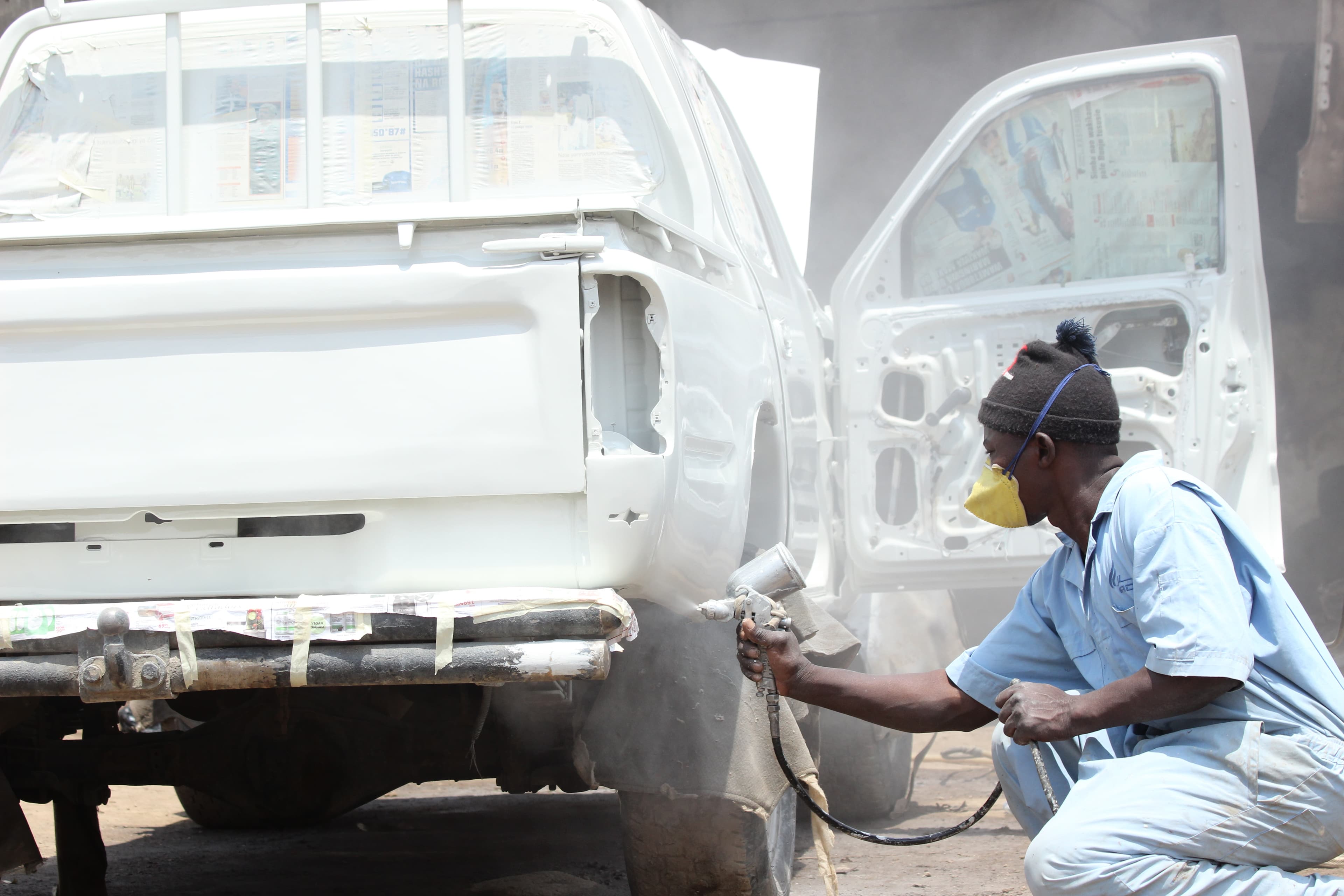 Spray painter refinishing a white bakkie at Van Wyk Panel Beaters